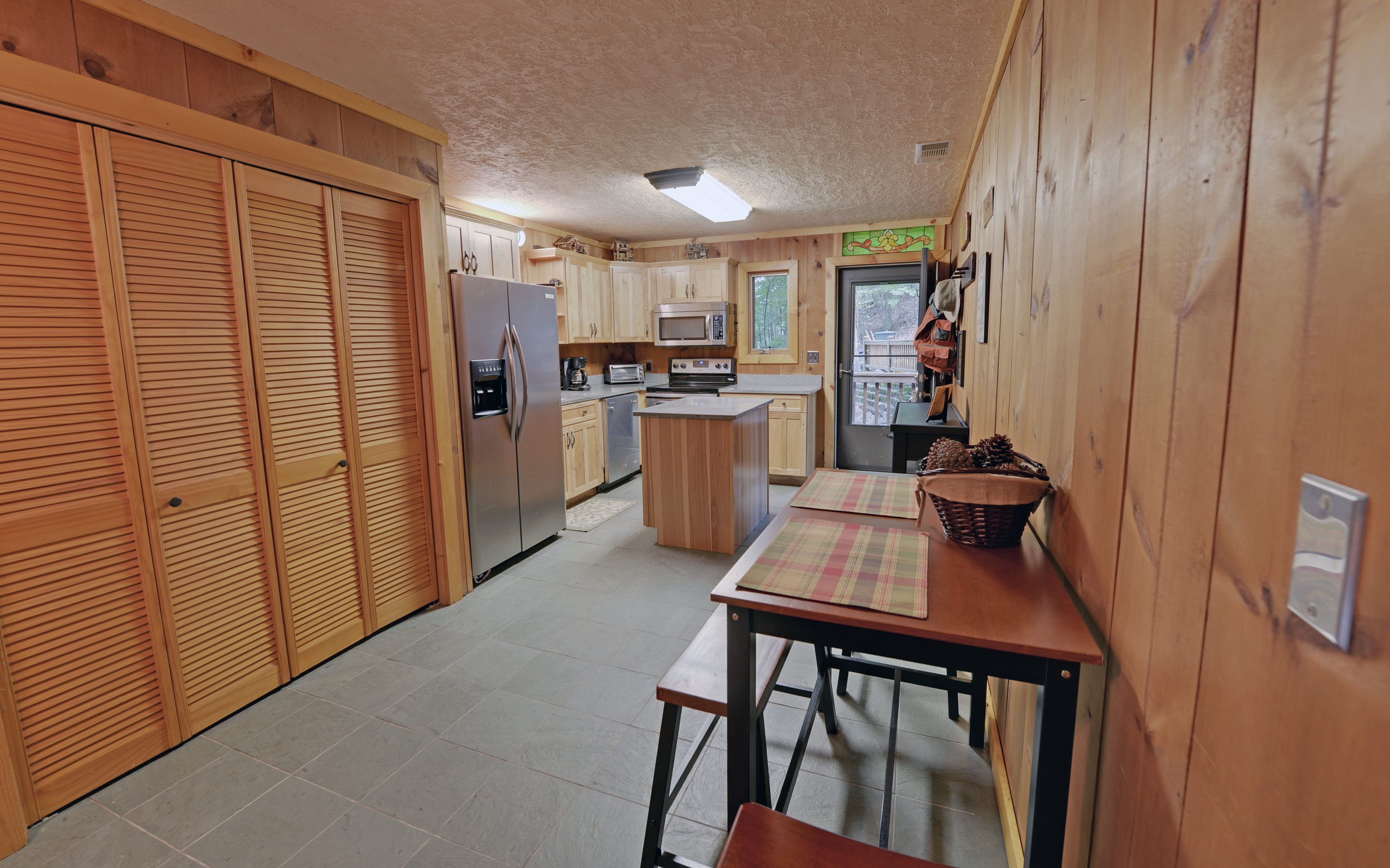 A compact kitchen with wooden cabinets, a refrigerator, a microwave, and a stove.
