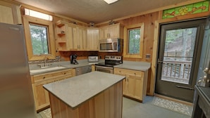 A kitchen with wooden cabinets, a microwave, an oven, a refrigerator, and a large island. - White Water River Cabin near Helen, GA-Kayak, tube, fish, hike, in wine country (Cleveland)