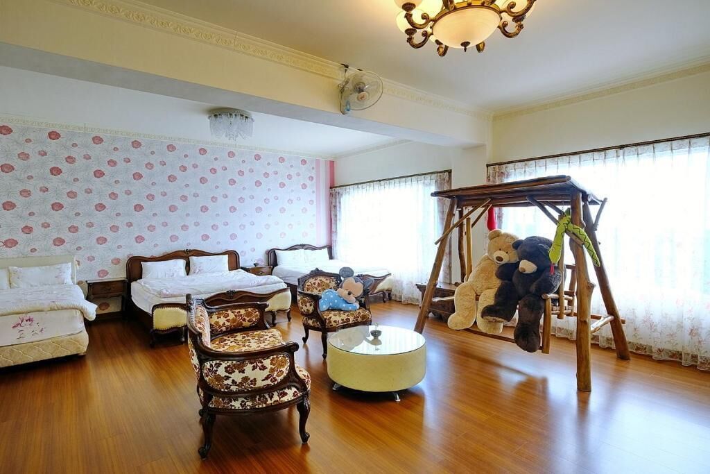 Una habitación con dos camas, piso de madera, un candelabro y un columpio de osito de peluche.