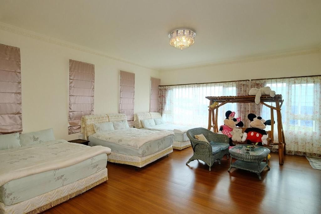 Um quarto espaçoso com duas camas, um candelabro e um balanço do Mickey Mouse.