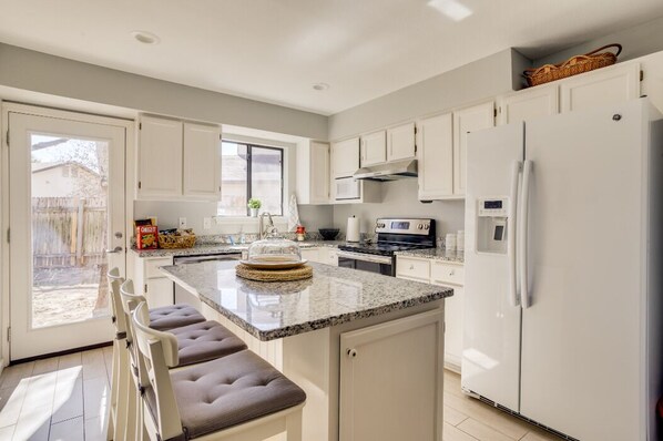 A modern kitchen with white cabinetry, a granite countertop, and a built-in island with seating.