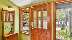 Una puerta de madera con un panel de vidrio, una pequeña ventana con marco de metal y una lámpara fijada a la pared.
