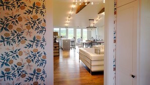 Eine moderne Küche mit Holzausstattung, eine Essecke mit heller Möbel und ein Blick ins Freie durch große Fenster.