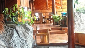 A wooden interior with a stone wall, a wooden bench, a table with a bowl, and a staircase leading to an upper level.