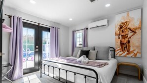Ein Schlafzimmer mit einem Bett, einem Fenster, einer Klimaanlage und einem Gemälde.