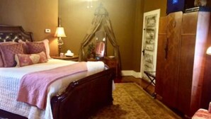 A bedroom with a bed, bedside table, lamp, canopy bed, wardrobe, and a ceiling fan. - Mary Kate Doyle Suite (Granbury)