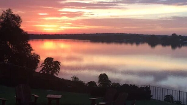 A lakeside view at sunset with outdoor seating and a fire pit. - Mary Kate Doyle Suite (Granbury)