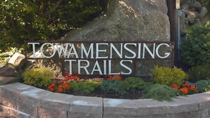 A sign for 'TOWAMENSING TRAILS' with a stone border and red flowers. - Luxury, Hot Tub,Fireplace,Pool Table,Pet Friendly,No Security Deposit! (Albrightsville)