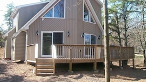 A two-story house with a wooden deck, large windows, and a chimney. - Luxury, Hot Tub,Fireplace,Pool Table,Pet Friendly,No Security Deposit! (Albrightsville)