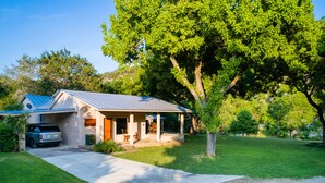 A single-story house with a covered porch, a car parked in the driveway, and a well-maintained lawn.
