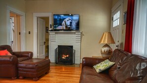 Una sala de estar con chimenea, sofás de cuero, un televisor y una lámpara.