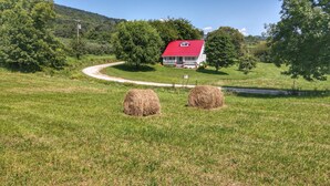 Paisaje rural con una casa, fardos de heno y un camino sinuoso.