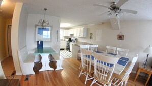 A spacious kitchen with white cabinets, a dining table with chairs, and a ceiling fan.