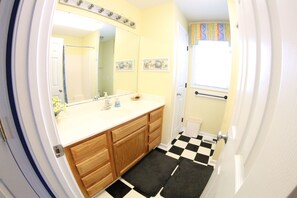 A bathroom with a checkered floor, wooden cabinets, a white sink, and a mirror above it. - Pet friendly Leeward Cottage: Only a Few Steps to the Beach (Carolina Beach)