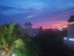 A sunset over a residential area with buildings and palm trees.