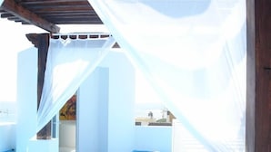 Een kamer met een bed, een klein tafeltje en uitzicht op zee.