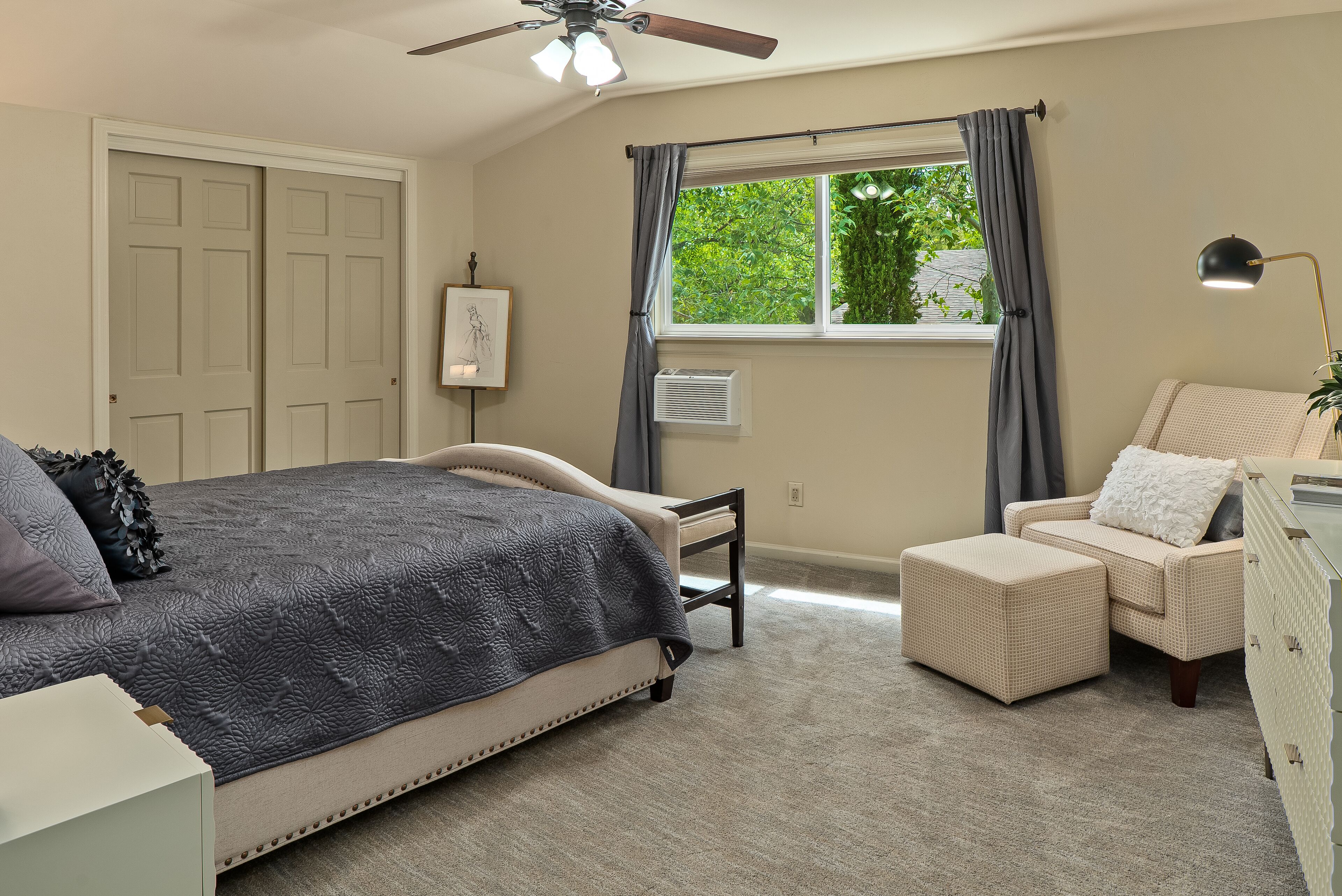 A bedroom with a bed, a chair, a dresser, and a window with curtains.