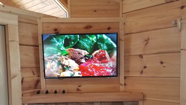 Interior de madera con una televisión sobre una chimenea de piedra.