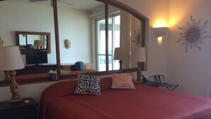A hotel room with a large bed, two bedside lamps, a mirror, and a sun decoration on the wall. - ONLY TRUE BEACH FRONT Condo in REAL La Paz!  Full Sunset View, 2 Pools, Pool Bar (La Paz)