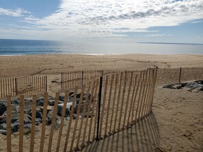 A sandy beach with a wooden fence and rocks. - Upscale Cottage On The Atlantic Ocean, Feet in Sand (Newbury)