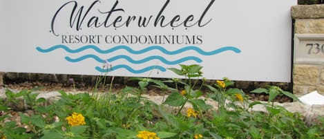 A sign for Waterwheel Resort Condominiums with a wave design and a sun.