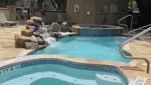Zona de piscina con dos jacuzzis y una cascada.