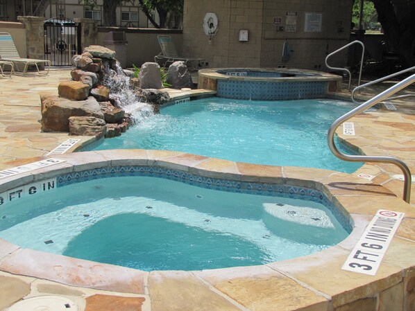 A pool area with two hot tubs and a waterfall feature. - POOLSIDE PARADISE!! WATERWHEEL CONDO 2 POOLS/4 HOT TUBS/NEW BRAUNFELS (New Braunfels)