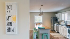A modern kitchen with a central island, pendant lights, and a view of the outdoors. - Large beautiful Farmhouse in the heart of PEC - 20 minutes to Sandbanks (Prince Edward)