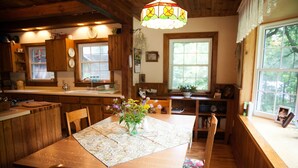 A wooden kitchen with a dining table, chairs, and a hanging light fixture.