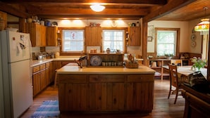 A rustic kitchen with wooden cabinets, a central island, and a dining area with a table and chairs.