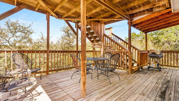 A wooden deck with outdoor furniture, a grill, and a staircase leading to an upper level. - Spacious Ranch Lake Retreat Hot Tub, Tesla Charger (Canyon Lake)
