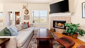 A living room with a sectional sofa, a fireplace, a television, and a deer head mounted on the wall. - Spacious Ranch Lake Retreat Hot Tub, Tesla Charger (Canyon Lake)