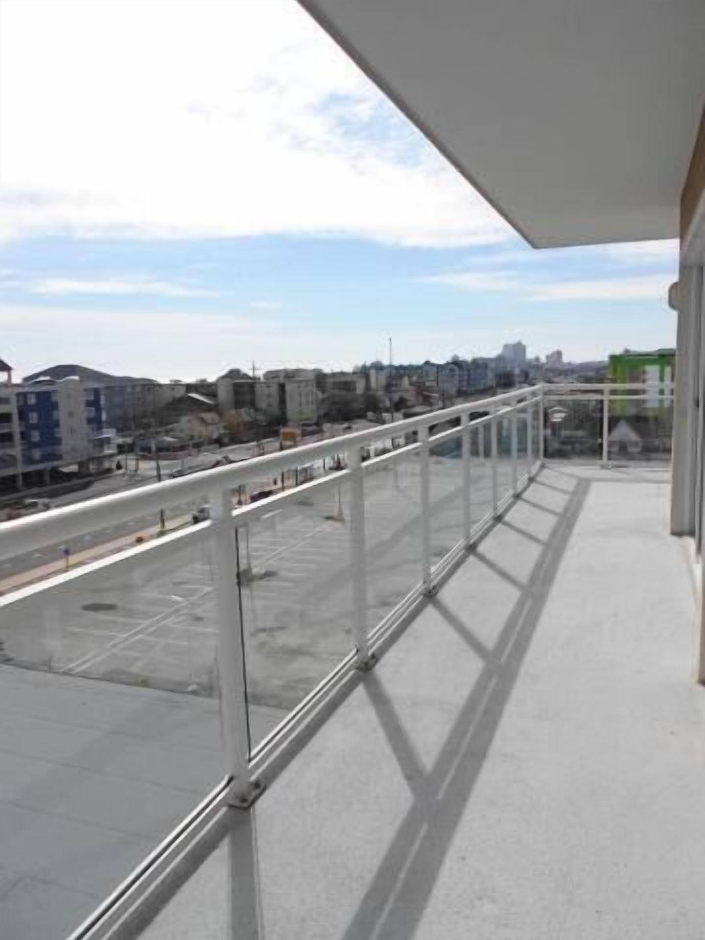 A balcony with a clear view of the cityscape, including buildings and a road.