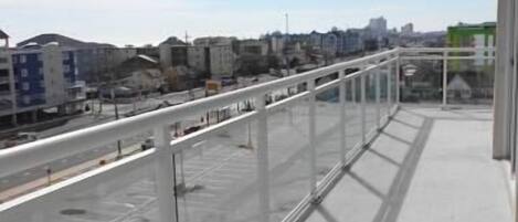 A balcony with a clear view of the cityscape, including buildings and a road.