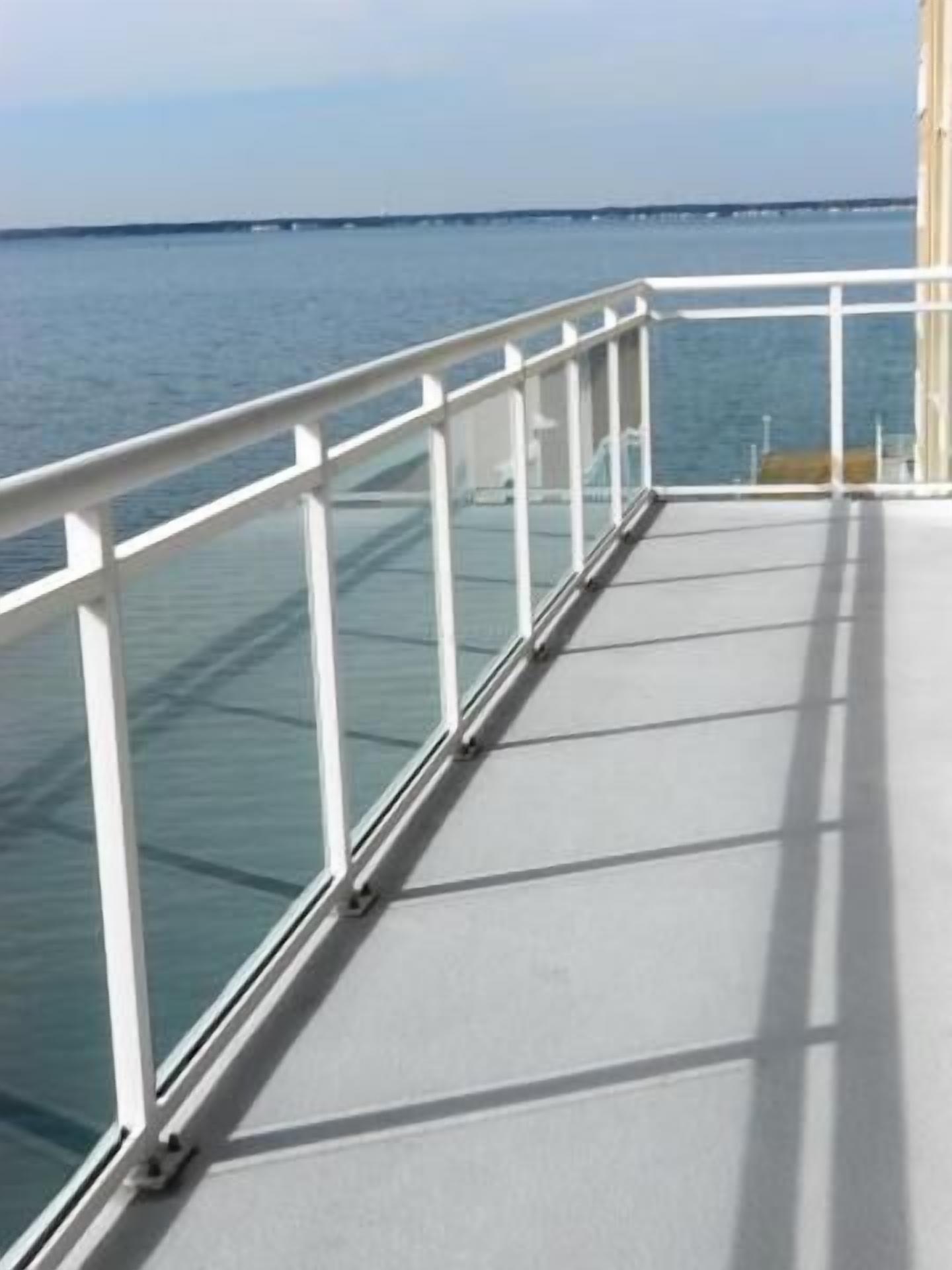 Una terraza con barandilla de cristal que da a un cuerpo de agua.