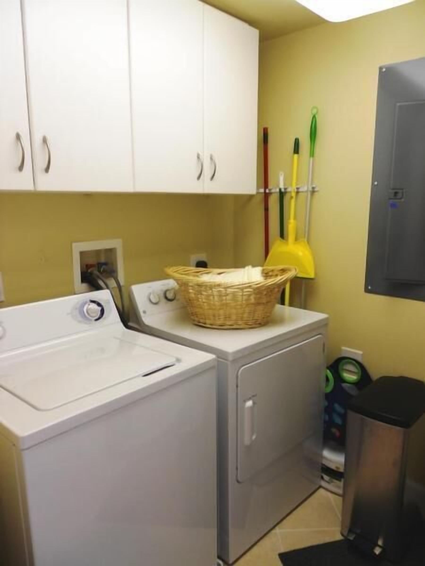 A laundry area with a washing machine, dryer, and a basket on the dryer.