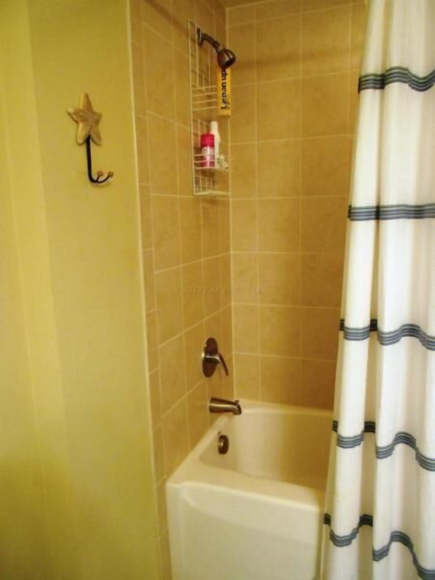Un baño con bañera, cabezal de ducha y un adorno con forma de estrella en la pared.