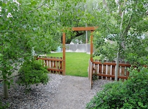 A wooden pergola with a gravel path leading to a wooden gate. - Immaculate, homey and perfectly located for your stay in downtown Ennis. (Ennis)