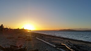 En strand med en solnedgång, en klar himmel och ett bergskedja i fjärran.