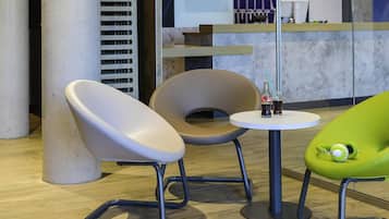 A modern interior with a round table, two chairs, a pillar, and a counter with a patterned cloth.