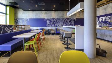 Un intérieur de restaurant moderne avec des tables hautes, des chaises colorées et un espace bar.