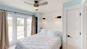 Une chambre à coucher avec un lit, un ventilateur de plafond et une porte.