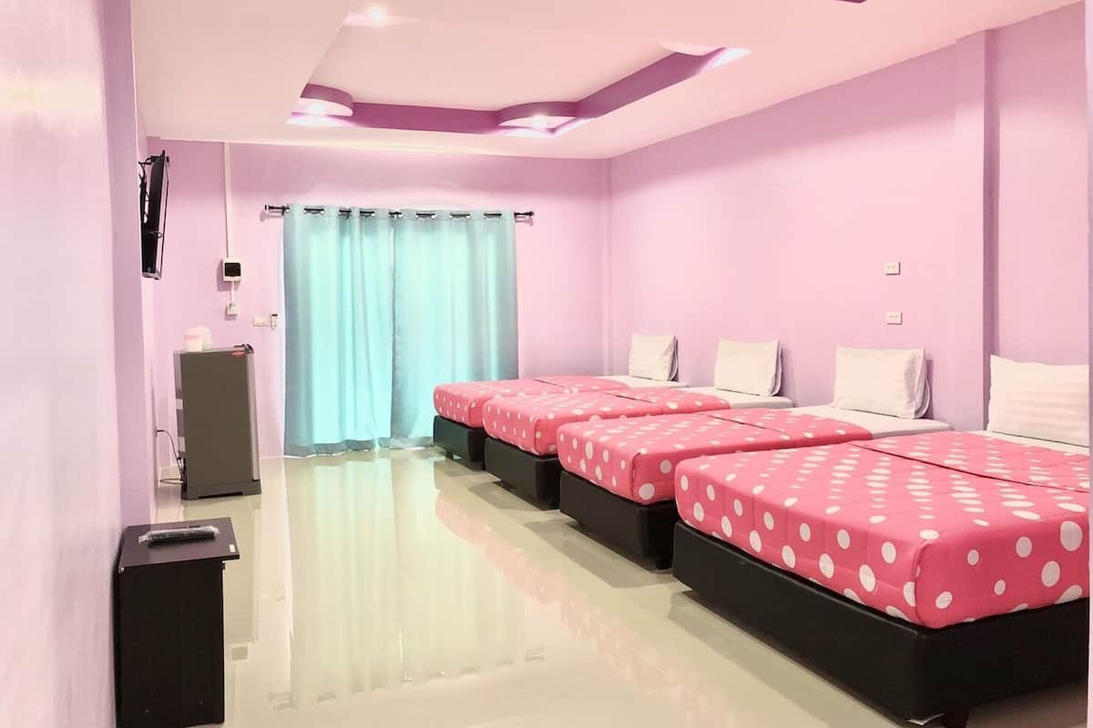 A hotel room with two beds, a desk, a trash bin, and a window with curtains.