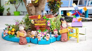 Decoración exterior con figuritas, un letrero de bienvenida y un molino.