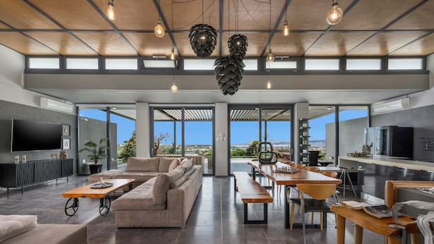 A spacious living area with a large sofa, a dining table, and a kitchen area with a refrigerator and stove. - 9 beds, 7 wc, sauna, jacuzzi, pool, cinema, bar, bbq, firepit, helipad, parking (Chania)