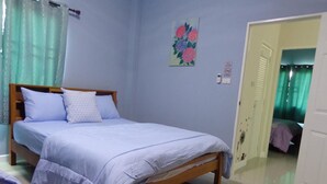 A bedroom with a wooden bed, light blue bedding, a painting on the wall, and a door leading to another room. - Sandy Home Sattahip (Sattahip)