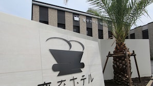 A sign for Henn na Hotel with a stylized pot symbol and Japanese characters.