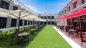 A courtyard with outdoor seating, green artificial turf, and modern buildings with large windows.