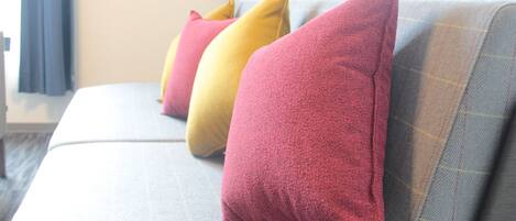 Un sofá con tres almohadones de distintos colores.