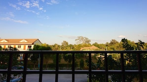 A balcony with a view of a building and trees. - Green Apple Villa (Sattahip)
